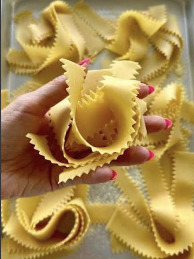 Wide fluted pappardelle held in a hand
